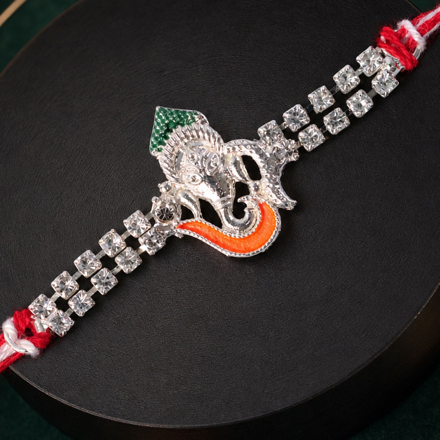 Traditional Rakhi showcasing Ganesha Charm, red stone accents and gift look for Gift