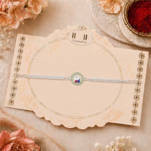 A silver bracelet with a green and white centerpiece featuring a deity, presented on a decorative beige card.