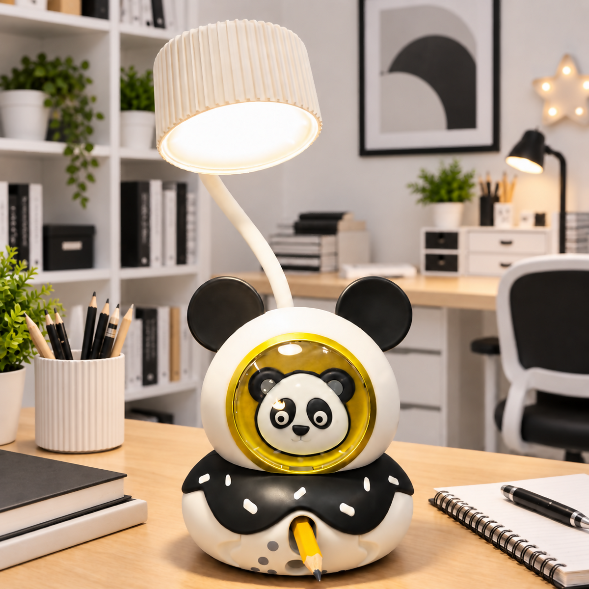 White and black panda-shaped desk lamp with a pencil sharpener and a flexible neck, illuminating a study table.