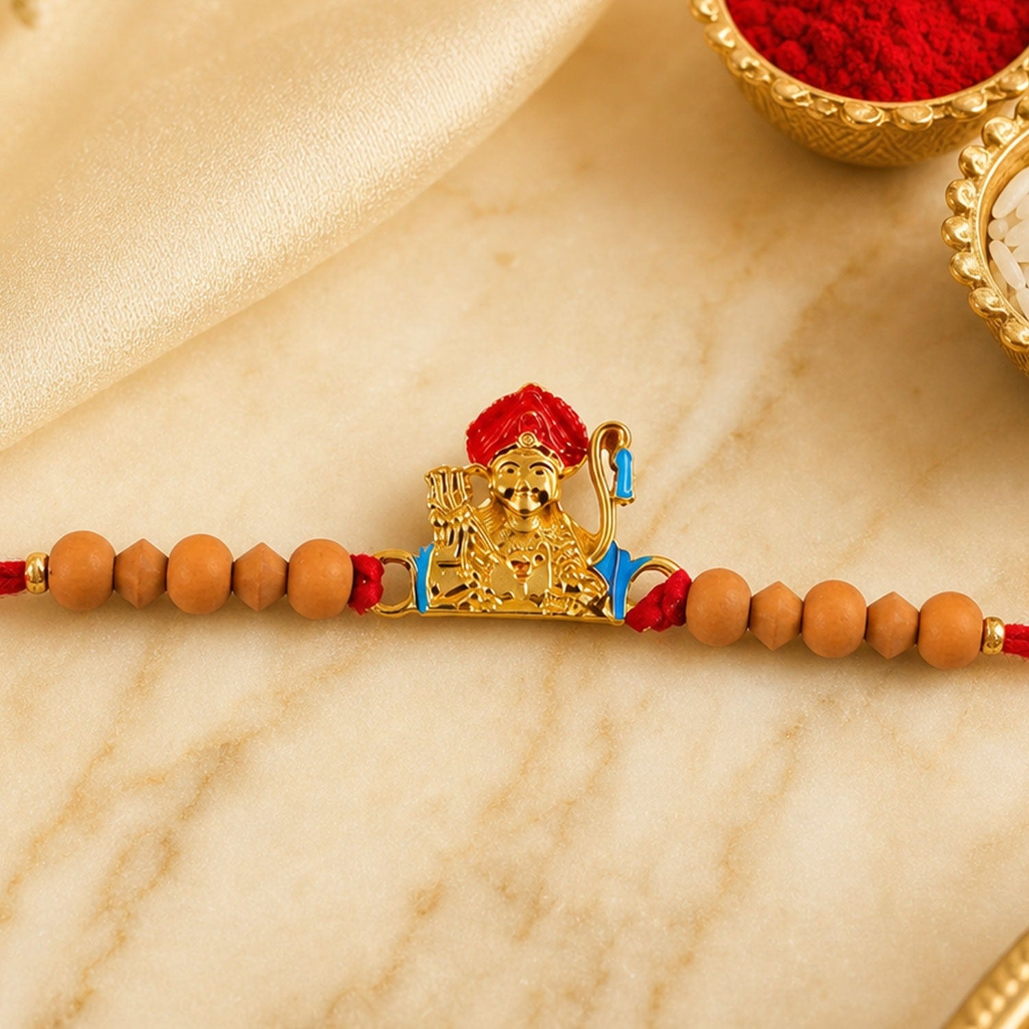 Auspicious golden deity Rakhi for brother with sandalwood beads for Raksha Bandhan.
