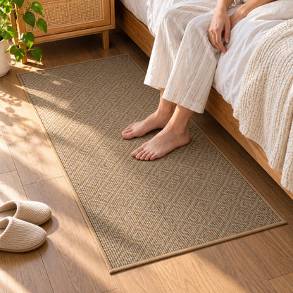 Bare feet rest on a textured brown runner mat with a diamond pattern beside a bed in a bedroom setting.