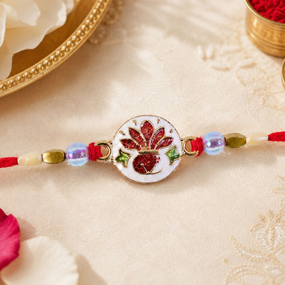 A red thread bracelet with a white ceramic disc featuring a red and green floral design, surrounded by light blue and gold