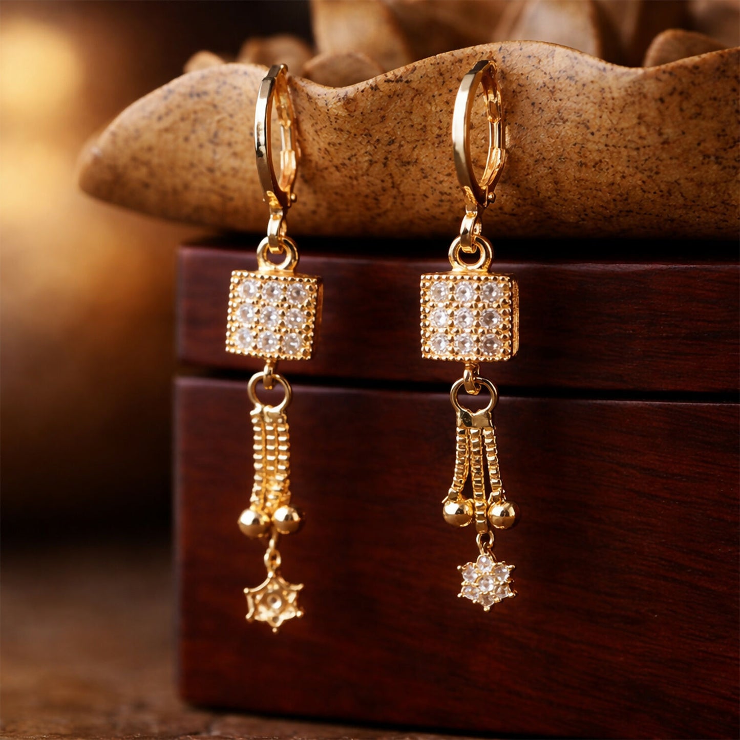 Elegant gold finish drop earrings with square stone cube and hanging star charm on white background