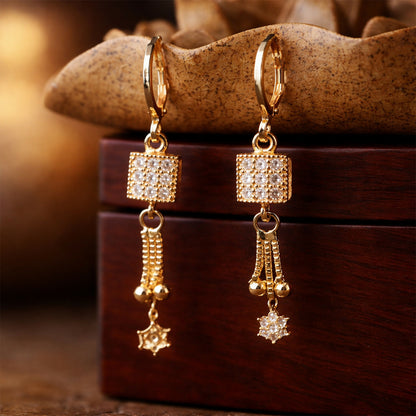 Elegant gold finish drop earrings with square stone cube and hanging star charm on white background