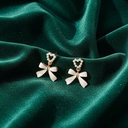 Vintage pearl heart and bow earrings with gold trim on white background