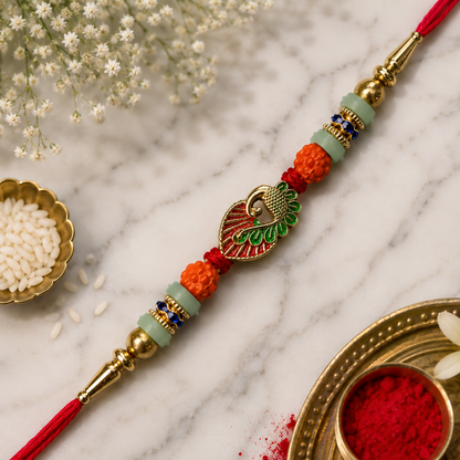 A red and gold bracelet with a peacock charm, orange and light green beads, and blue accents, surrounded by white flowers,