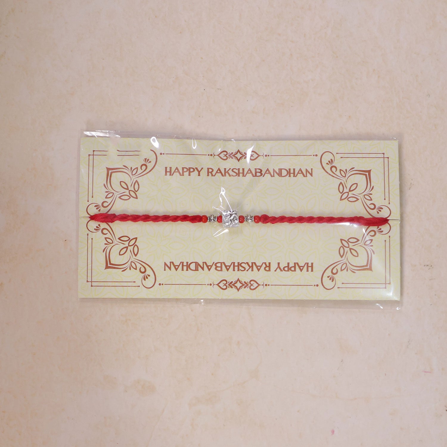 Red Thread Rakhi with a Bold Silver Om Pendant and Red Beads