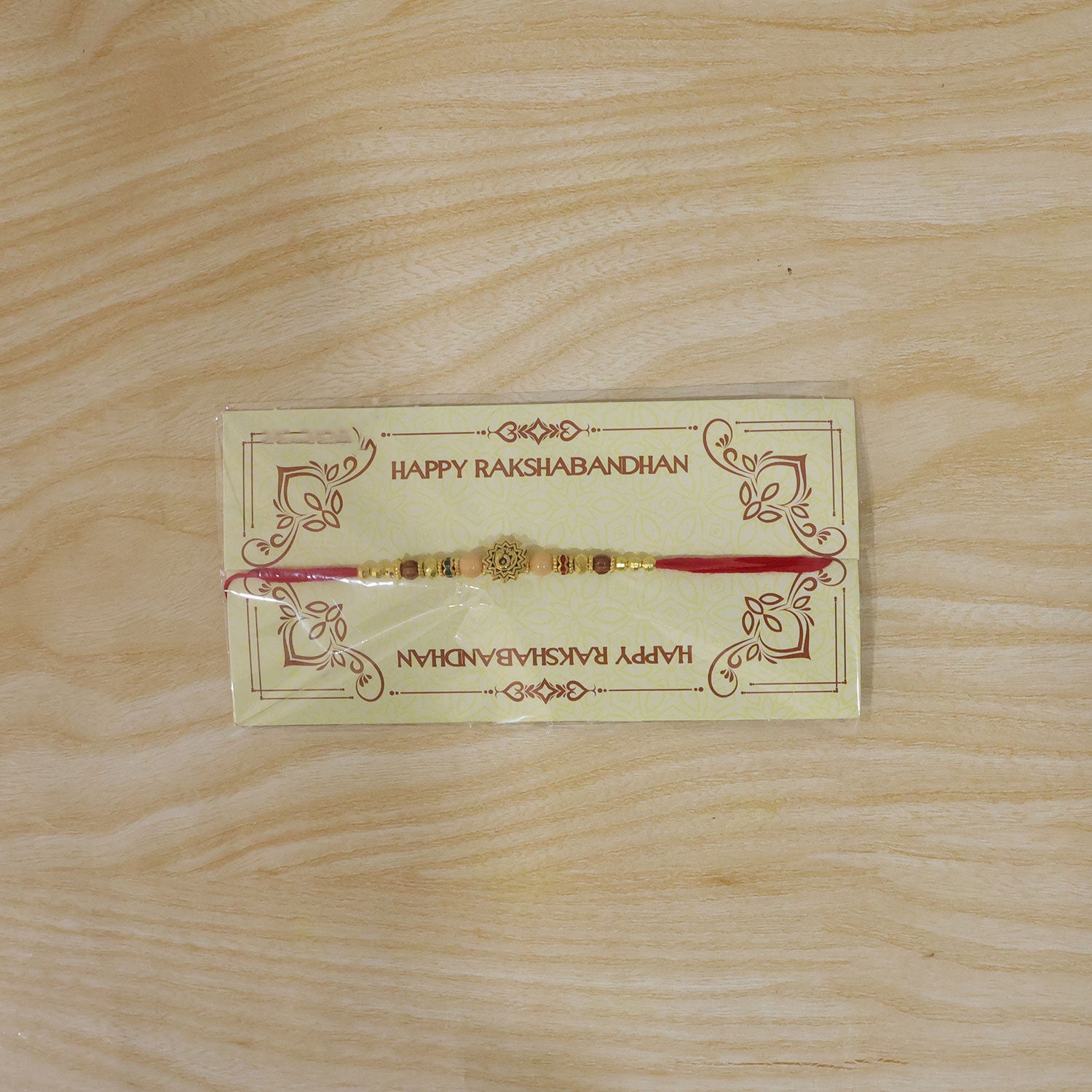 Om Sacred Symbol Golden Devotional Rakhi with Peach Beads and Red Thread