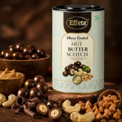 A tall tin of choco-coated nut butterscotch stands next to a wooden bowl filled with chocolate candies, cashews, and