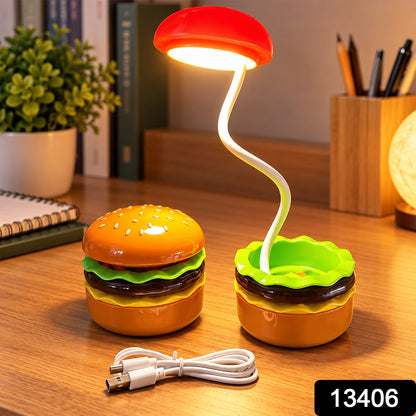 A burger-shaped lamp with a red top and a flexible white arm illuminates a desk with a white USB cable and a number tag.