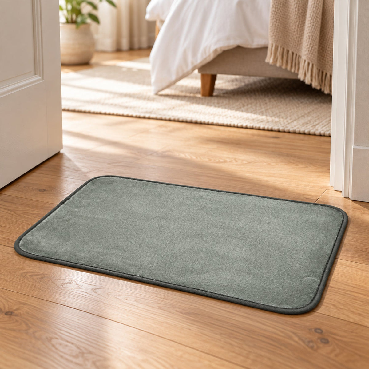 A gray rectangular floor mat placed on a wooden floor, partially visible through an open door.