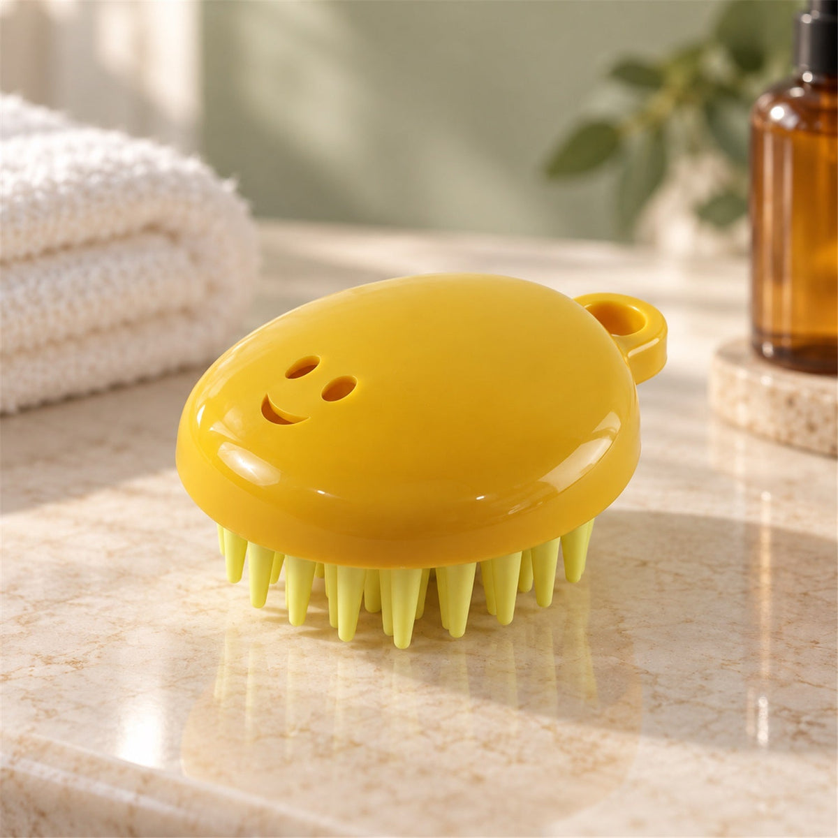 A yellow silicone scalp brush with light green bristles sits on a marble countertop next to a white towel.