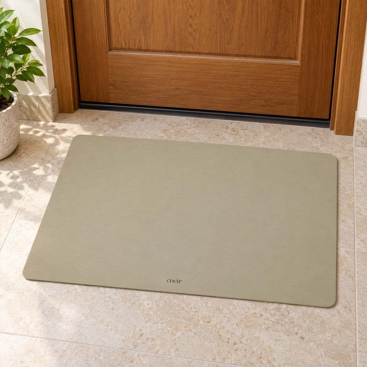 A light beige rectangular mat is positioned on tiled flooring in front of a closed wooden door.