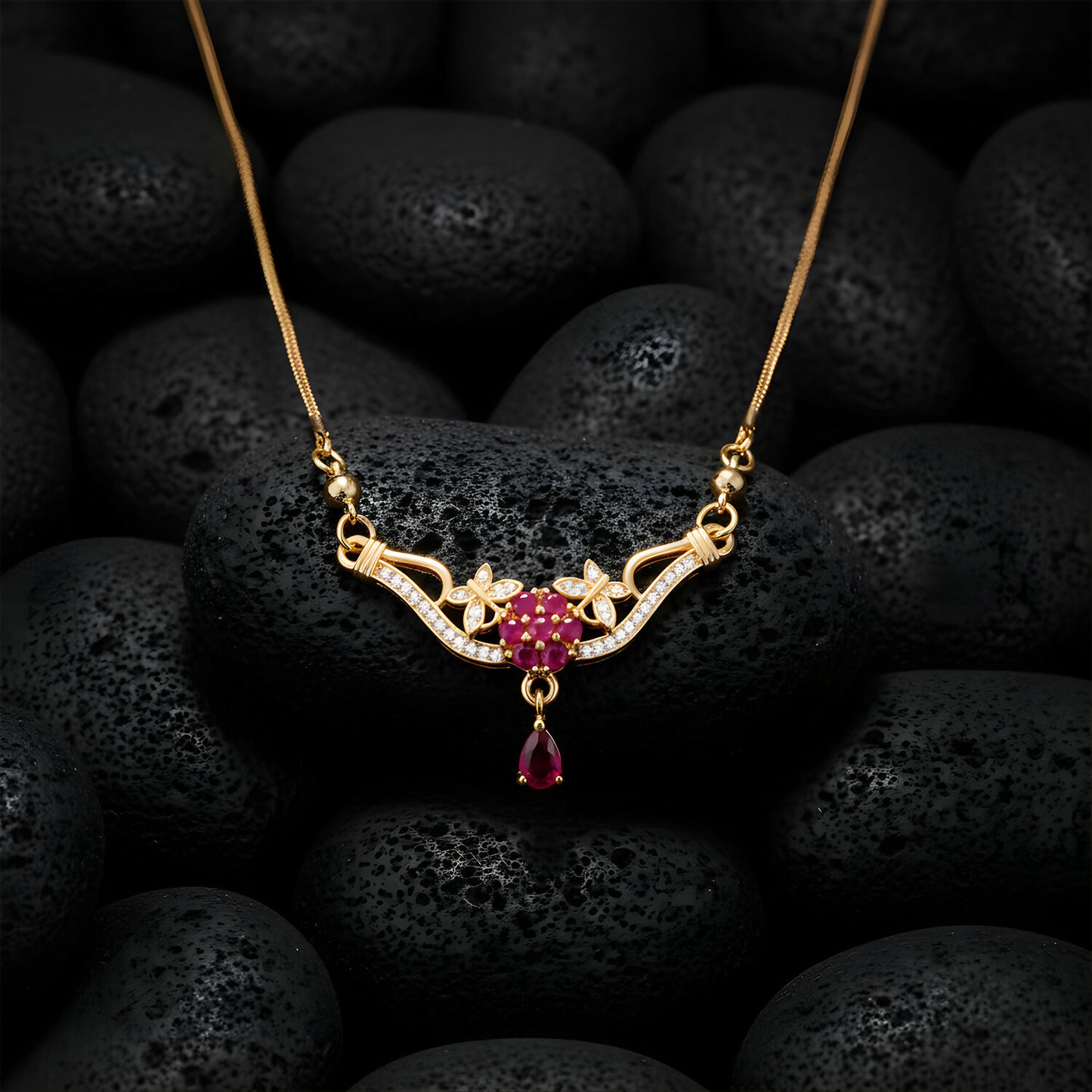 Gold finish floral necklace with red stone drop pendant worn on model's neck
