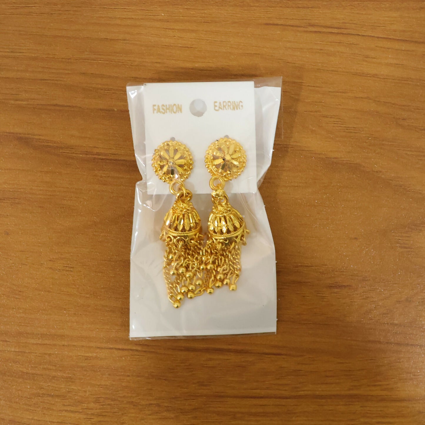 Detailed view of gold plated jhumka earrings with chain tassels