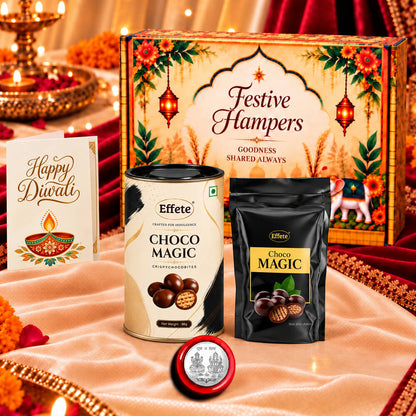 A festive hamper box, two chocolate containers, a silver coin, and a Happy Diwali card on a white cloth.