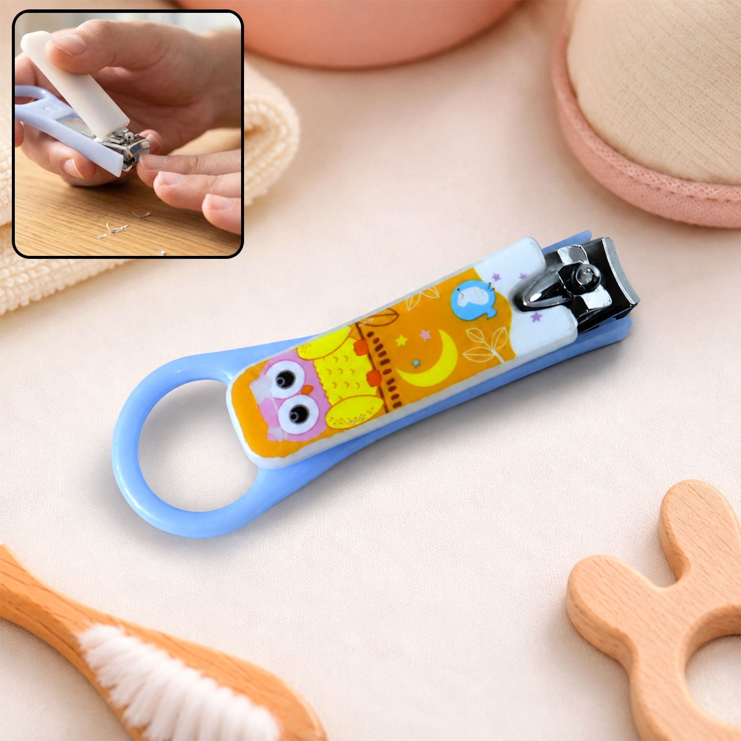 A light blue baby nail clipper with a yellow and white owl design, shown with an inset of it being used.
