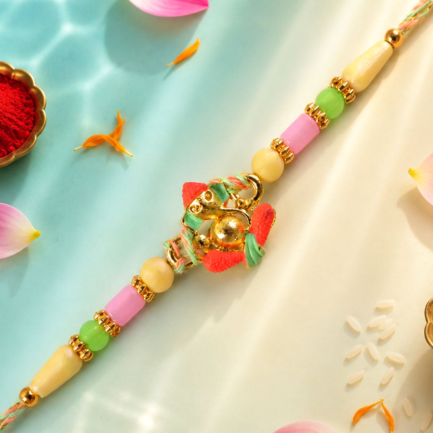Gold Ganesha Charm Rakhi with Coral and Green Accents