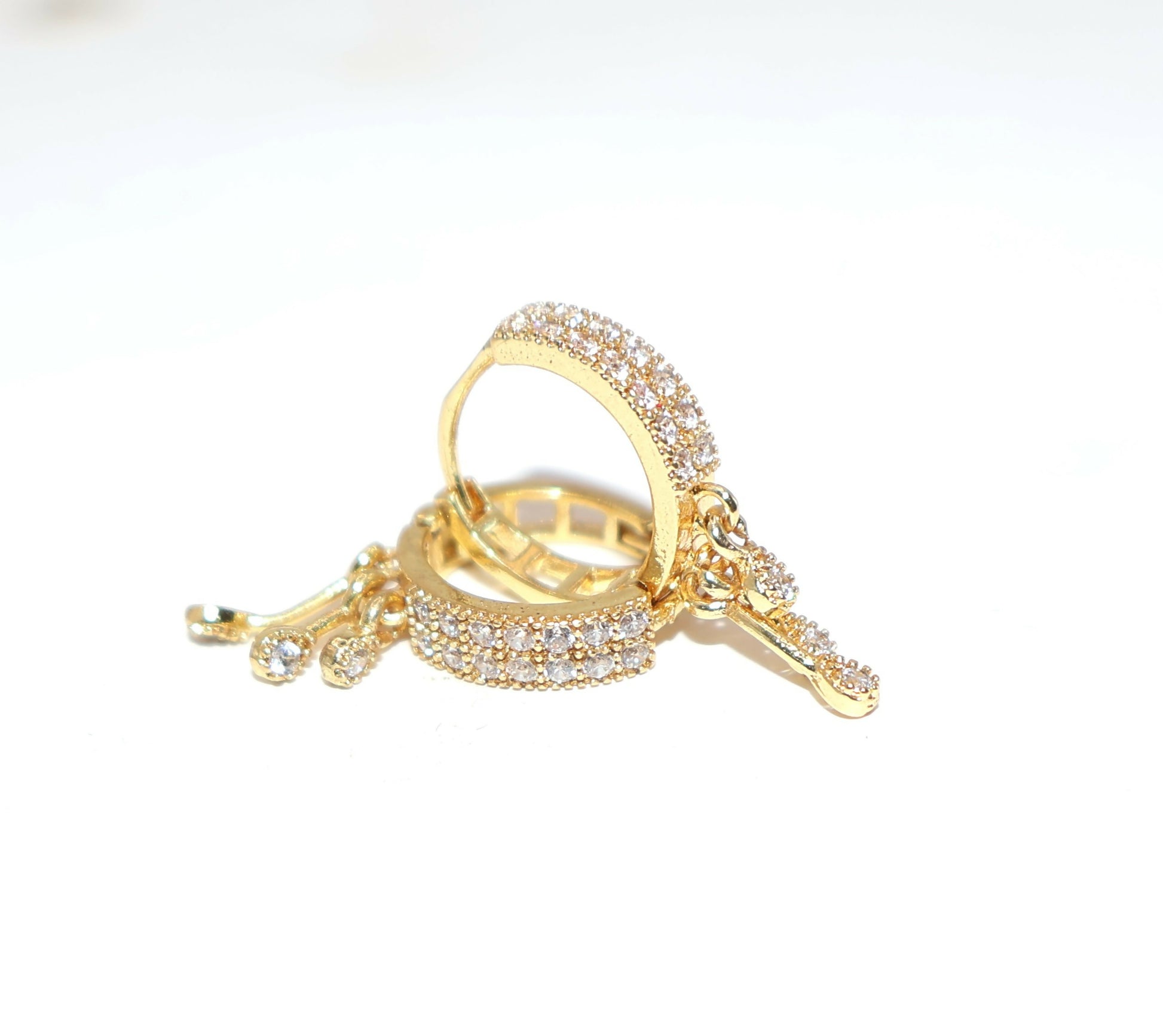 Close-up of swan design on gold plated dangle huggie hoop earring with CZ embellishments