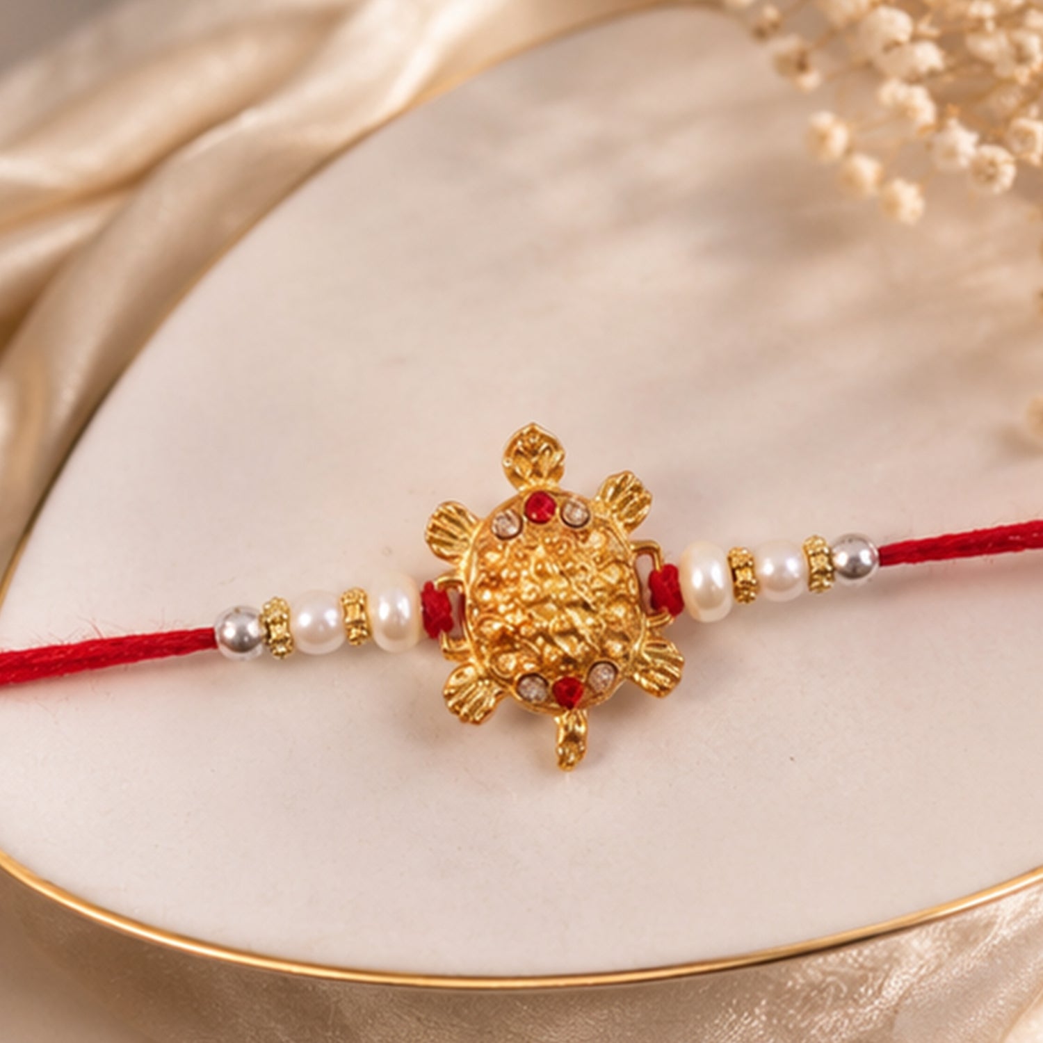 Gold Turtle Charm Rakhi with Pearl Sides and Red Mauli Thread