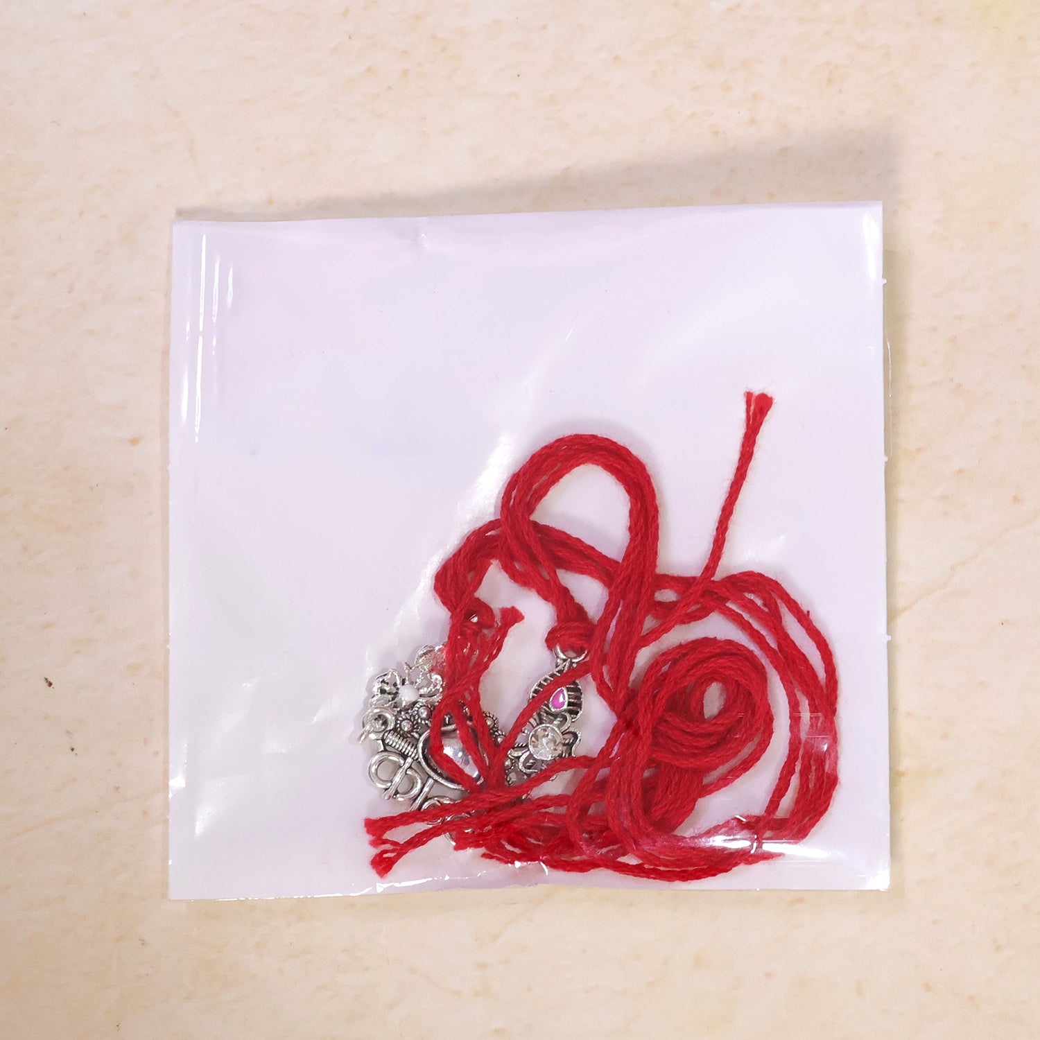 Silver-Toned Kanha Rakhi with Kundan-Style Stone, Crystal Accents & Designer Red Thread