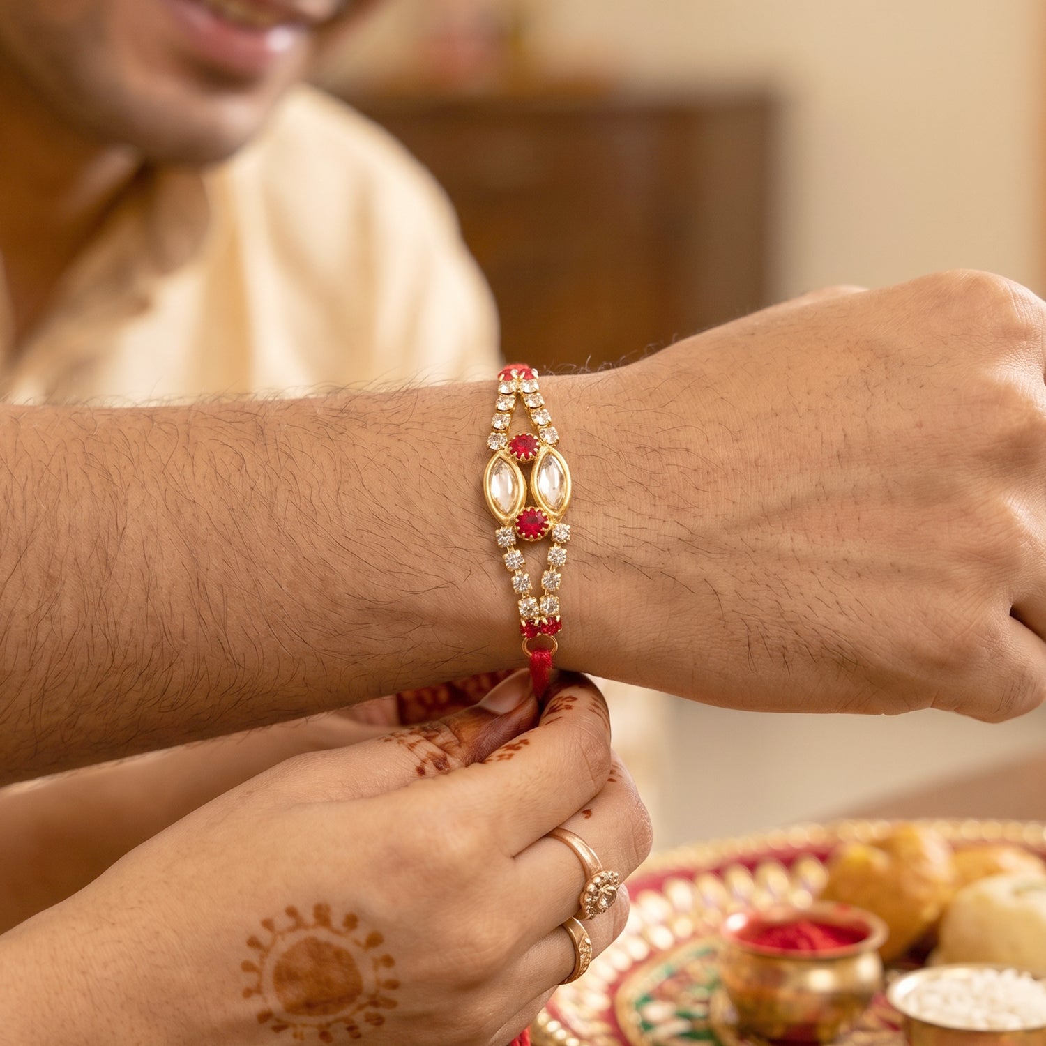 Oval Kundan Bracelet Rakhi with Red Blue Stones and Crystal Line
