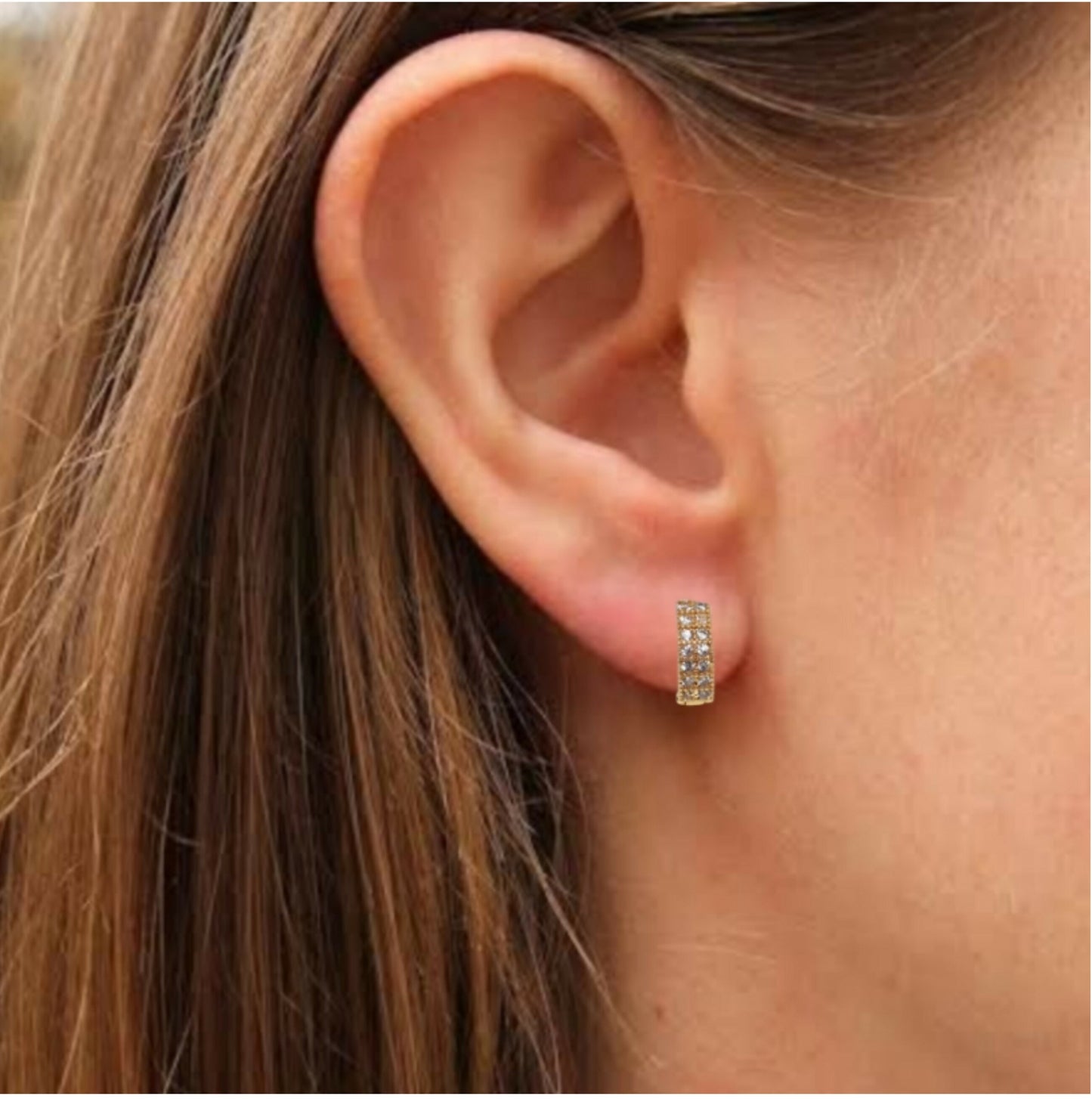 Close up of gold plated multicolored cubic zirconia stones on huggie hoop earrings