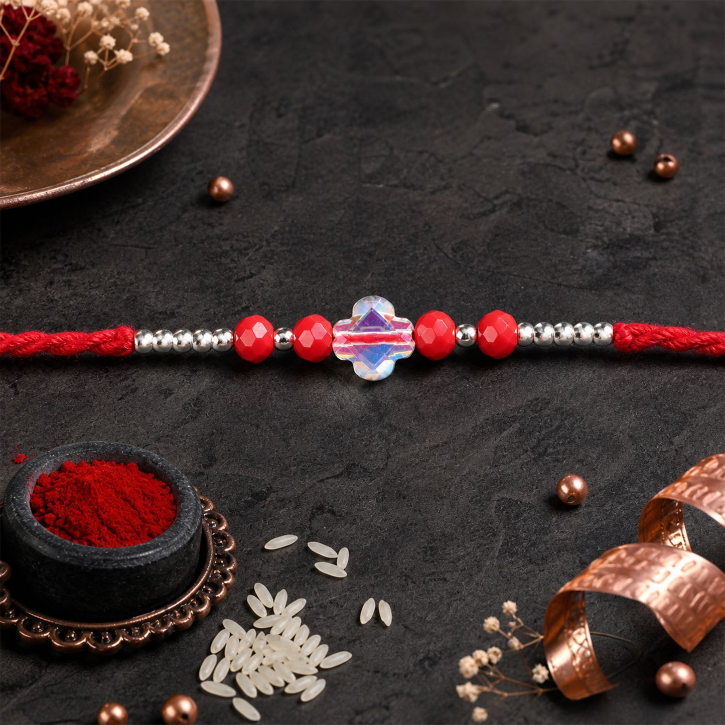 Red Thread Rakhi with Red Beads and an Iridescent Quatrefoil Crystal