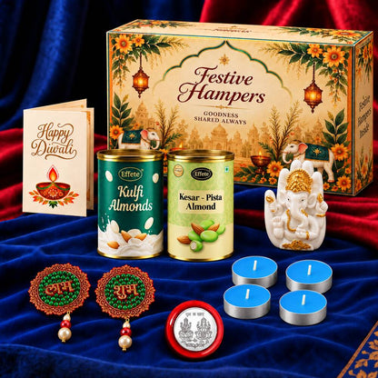 A Diwali gift box, Ganesha idol, almond tins, tealights, and earrings are displayed on a blue fabric surface.