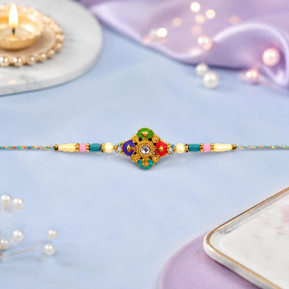 A single colorful Rakhi with a central floral design in green, blue, pink, and gold, adorned with a clear gem, is stretched