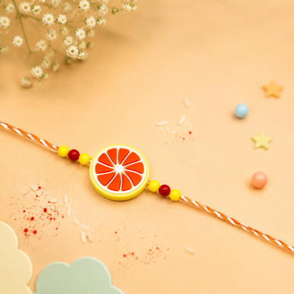 An orange and white citrus slice-shaped bracelet with red and yellow beads is centered on a light orange background with