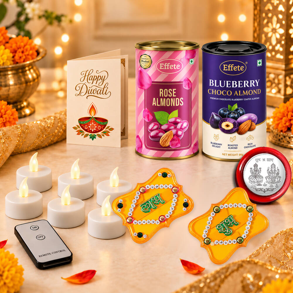 Two tins of almonds, a Diwali card, glowing LED tealights, a remote, and decorative Shubh-Labh pieces on a festive table.