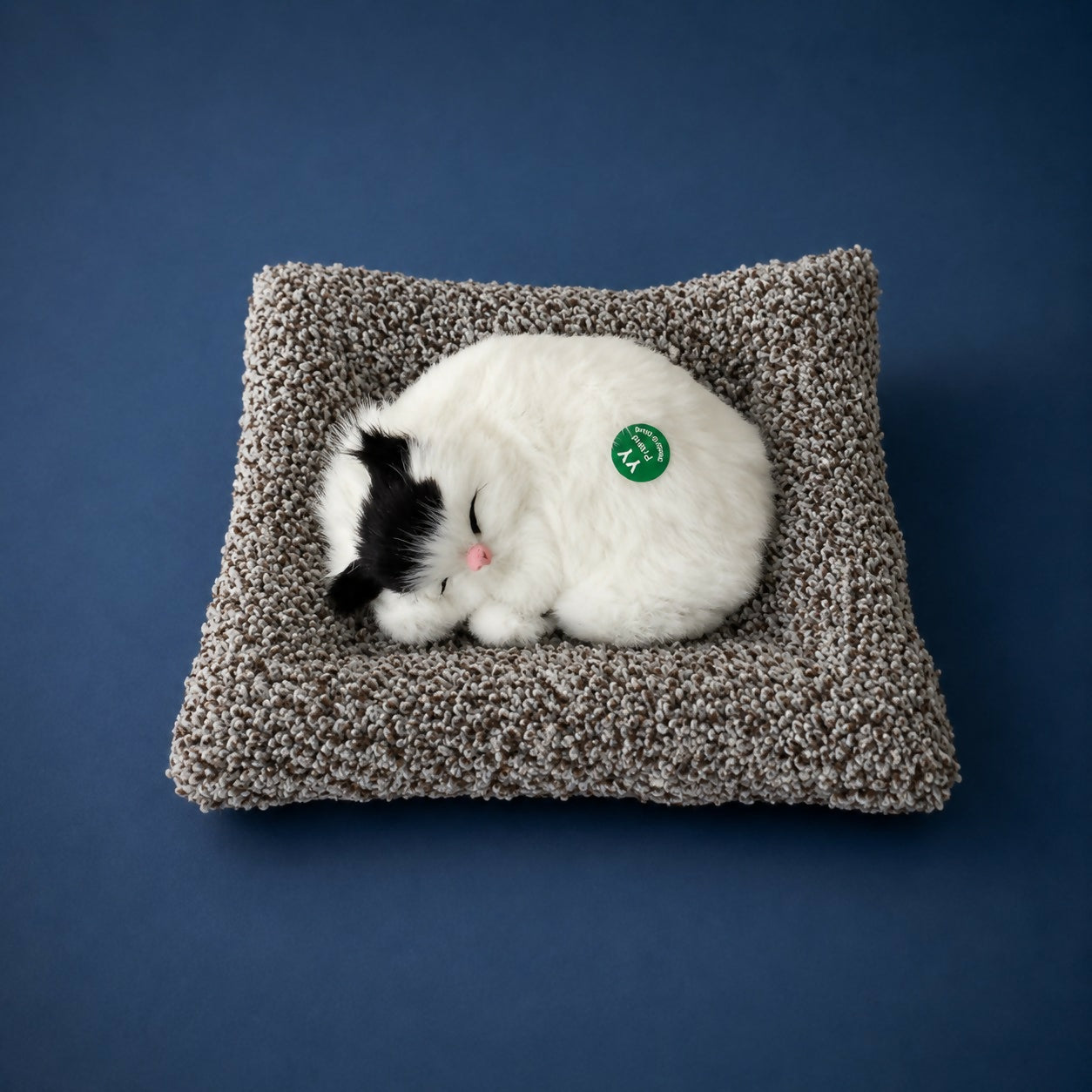 Sleeping cat plush toy displayed on desk for office décor