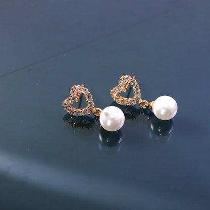 Side view of heart shape pearl earrings with delicate pearl drop accent