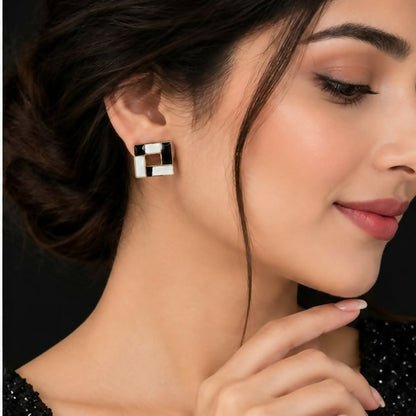 A woman models a single black and white square earring on her right earlobe.