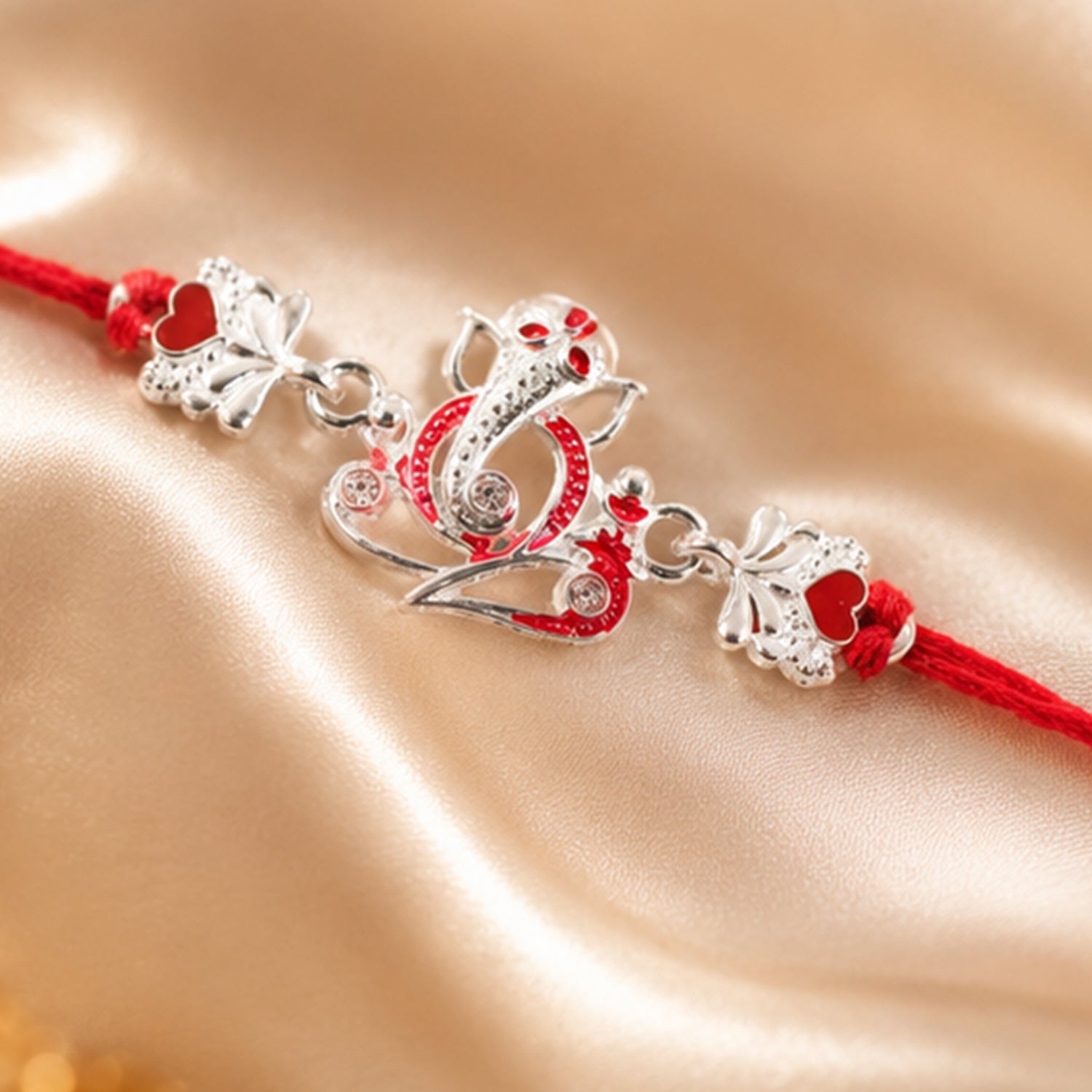 Silver Ganesha Rakhi with Red Stone Hearts and Deep Velvet Look