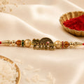 Krishna Rakhi – Peacock Flute Golden Centre & Red Beads