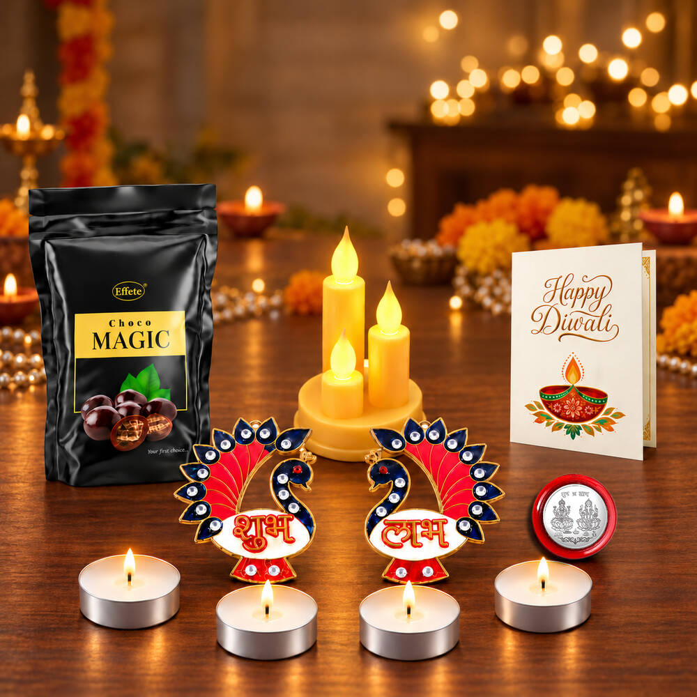 A Diwali gift box with chocolate, LED candles, tealights, peacock decor, a silver coin, and a greeting card on a wooden
