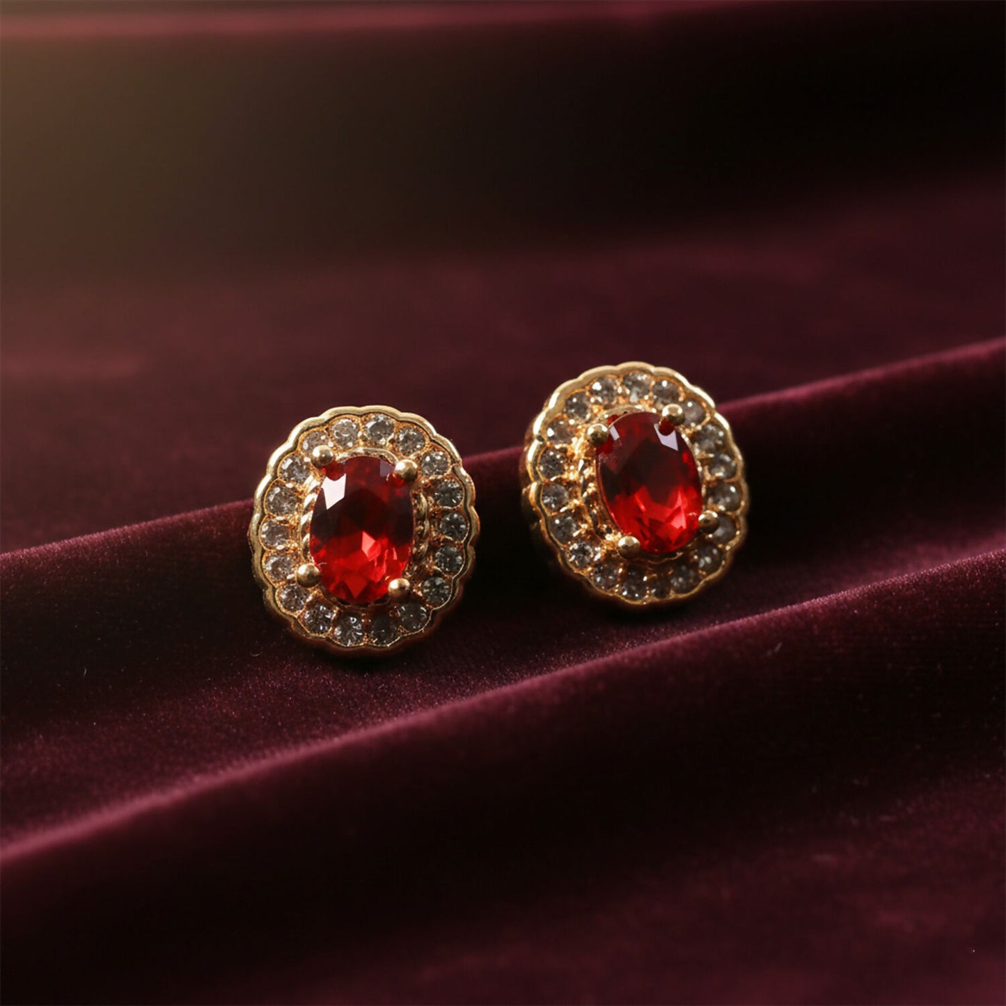 Elegant red stone stud earrings with crystal halo on a white background