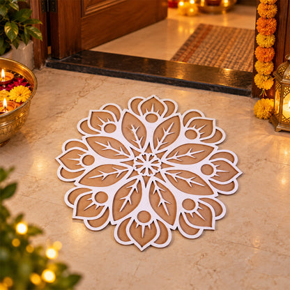A white and brown wooden rangoli stencil with a floral design on a light-colored floor, surrounded by lit candles and a