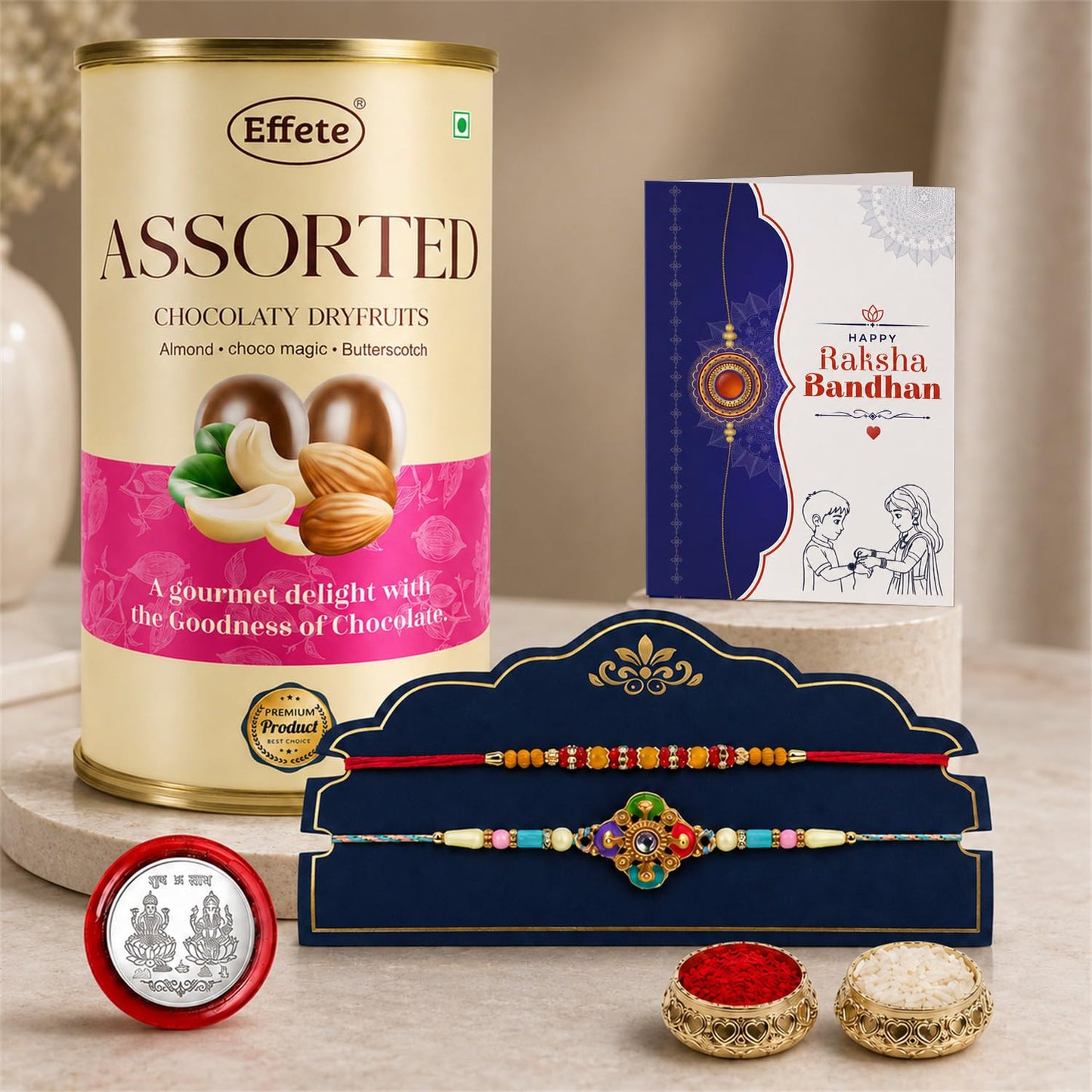 A tall beige tin of assorted chocolaty dry fruits, a blue Rakhi card, two colorful Rakhis on a blue stand, a silver coin,