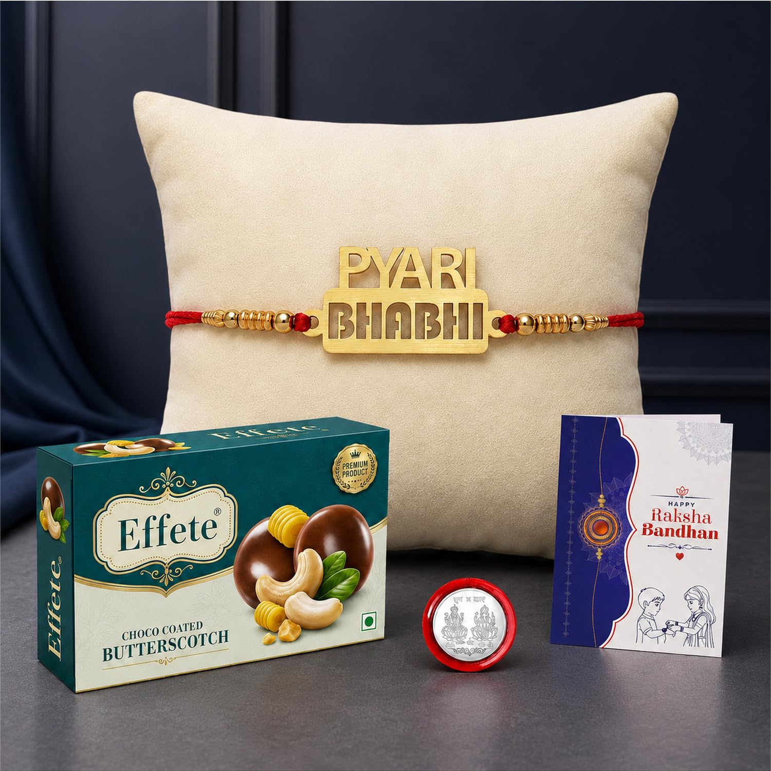 A Rakhi gift set with a gold-colored bracelet on a cream cushion, a green box of chocolates, a card, and a silver coin.