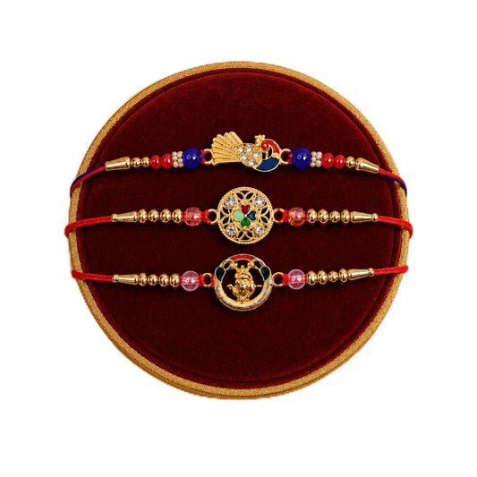 Three colorful bracelets with gold-colored beads and charms, one featuring a peacock, on a round red velvet cushion.