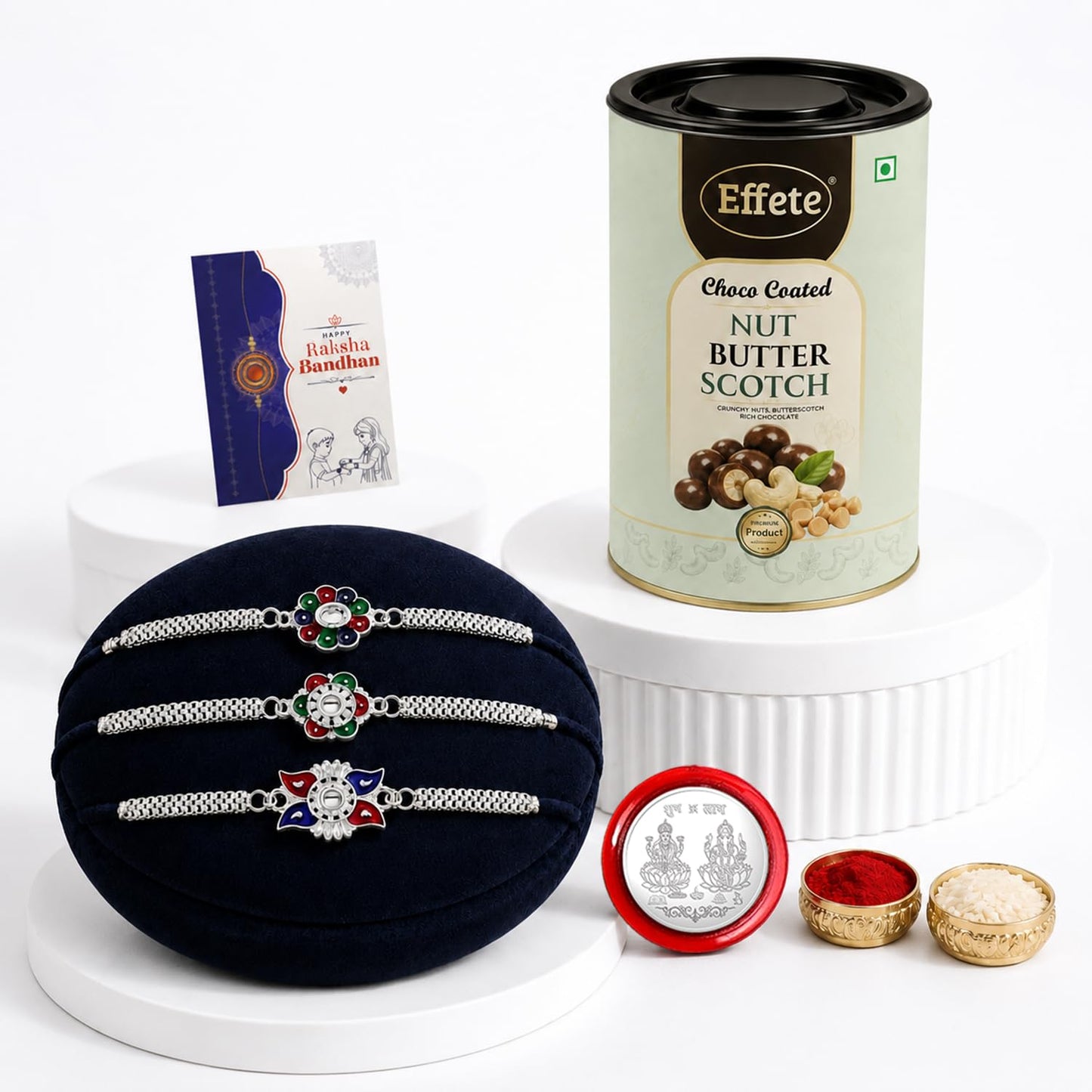 A navy velvet cushion holds three silver-toned bracelets with intricate, colorful centers, next to a chocolate tin, a