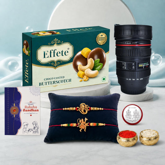 A Rakhi gift set with chocolates, a camera lens, a greeting card, two Rakhis on a blue pillow, and small bowls of kumkum and