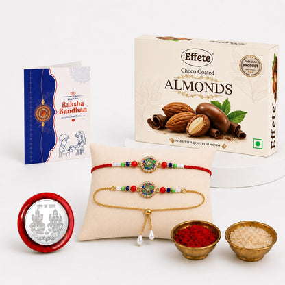 A gift set with two decorative bracelets, a box of chocolate almonds, a greeting card, and small bowls of rice and kumkum