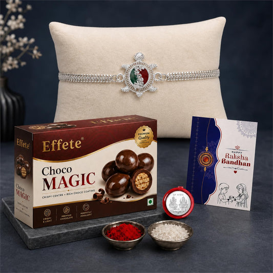 A silver-toned turtle Rakhi with red and green accents, a box of Effete Choco Magic, a greeting card, and small bowls of red