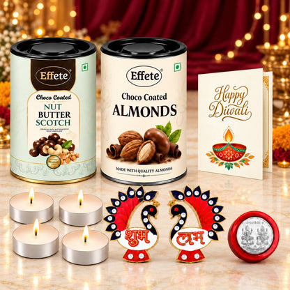 Two tins of chocolate-coated nuts, four glowing tealight candles, two red and blue peacock decorations, and a Happy Diwali
