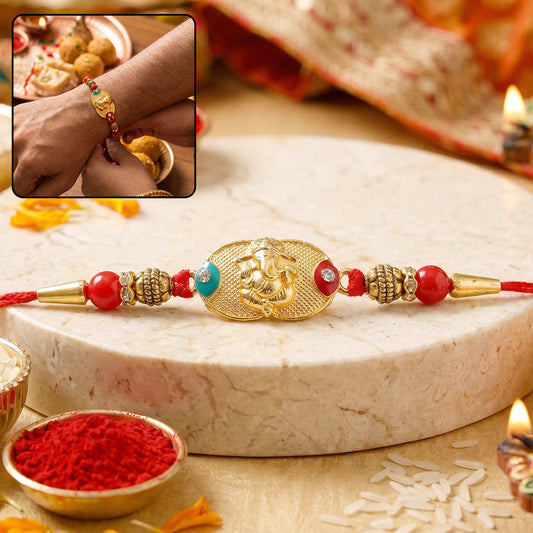 Golden Ganesh Rakhi with red and green beads on white background