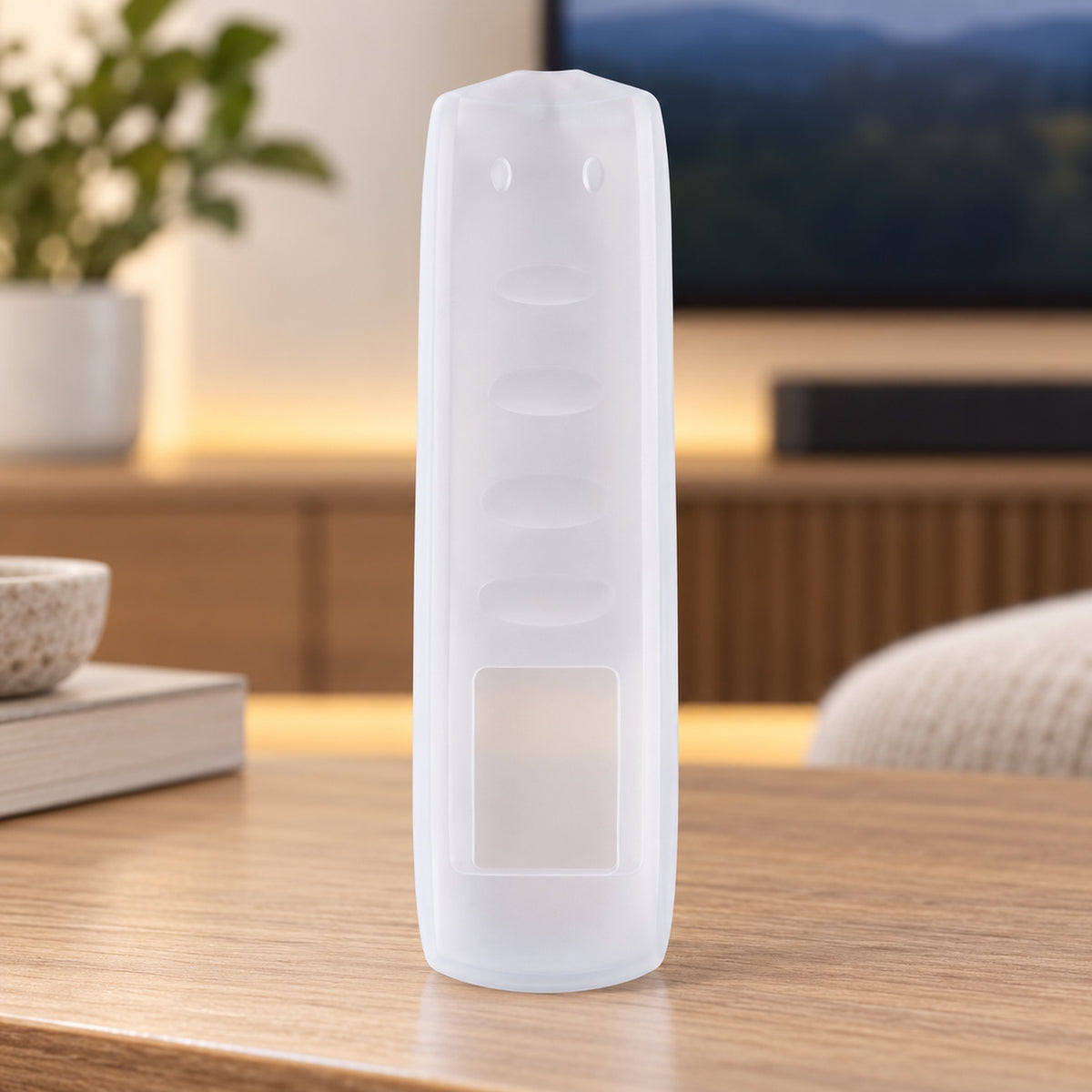 A translucent silicone remote control cover stands vertically on a wooden table in a home entertainment area.